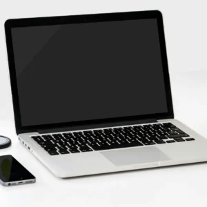 A minimalist workspace featuring a laptop, smartphone, and an apple on a clean white desk.